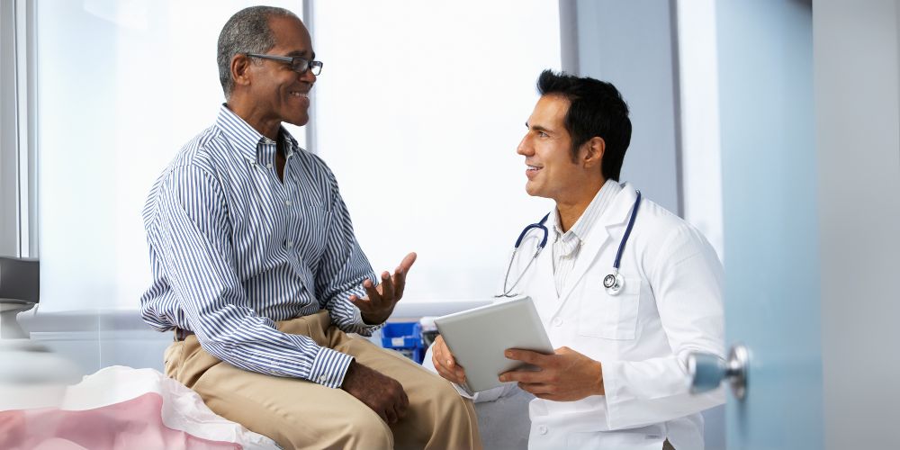 Man smiling while talking with his doctor